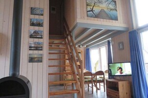 Eine Holztreppe führt zu einem Erker mit Fernseher und Kamin.