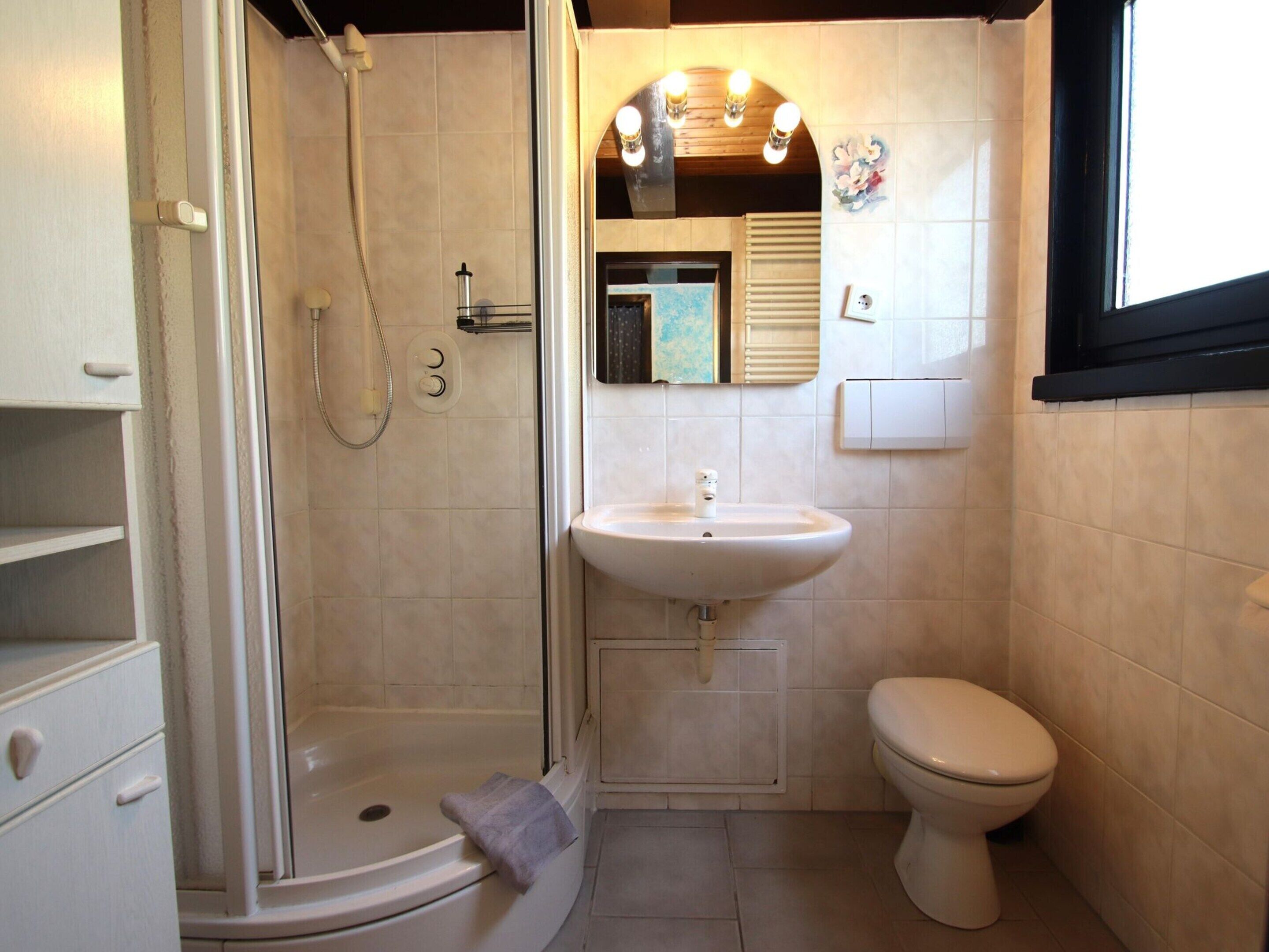 Een kleine badkamer met douche, toilet en wastafel.
