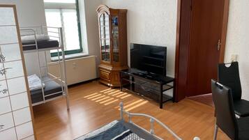 A room with a bunk bed, a TV on a stand, a wooden cabinet, and a door.