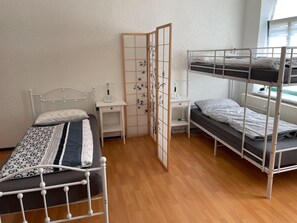 Une chambre de dortoir équipée de lits superposés, d’un bureau, d’une chaise et d’une cloison agrémentée de panneaux décoratifs.