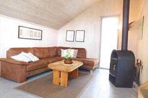 A cozy living room with a brown sofa, a wooden coffee table, and a black fireplace.