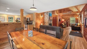 Une cuisine spacieuse dotée de meubles en bois, d’un mur d’accent en pierre et d’un coin repas avec une grande table et des bancs en bois.