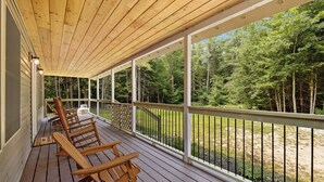 Une terrasse en bois avec des chaises et une vue sur une forêt.