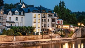 Un bâtiment historique à étages, une enseigne bien visible portant l’inscription « SEMOIS », et son reflet dans l’eau.