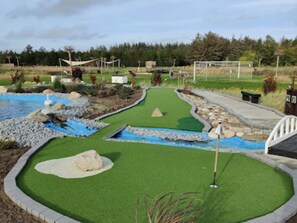 A miniature golf course with a putting green, sand traps, and a water hazard. - Holiday Home 4 km From the Coast (Blokhus)