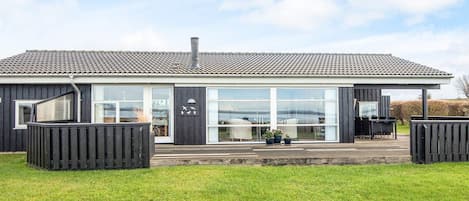 Un bâtiment moderne doté de grandes fenêtres, d’un toit plat et d’une pelouse verdoyante à l’avant.