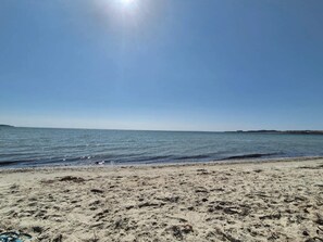 Ein Strand mit blauem Himmel und ruhigem Wasser.