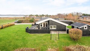 Una casa moderna con una terraza grande, un patio cercado y vista al mar.