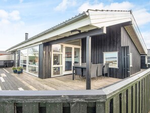 A modern house with a wooden deck, large glass windows, and a covered outdoor seating area. - 4 Star Holiday Home in Knebel (Knebel)