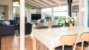 Amplia sala de estar con un gran ventanal, una mesa de comedor y un televisor al fondo.