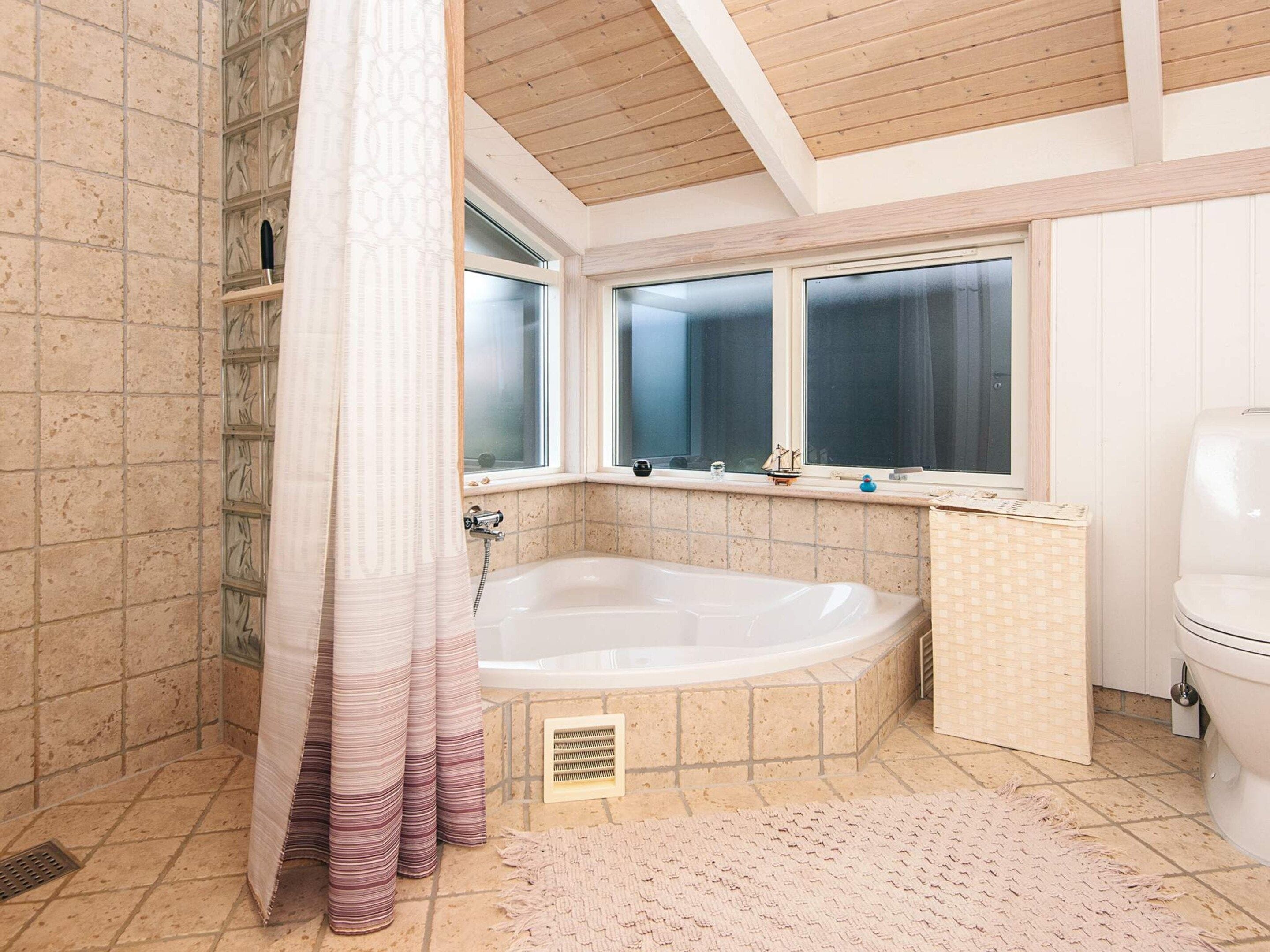Een badkamer met een bad, toilet en douchegordijn.