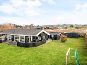 Une maison moderne dotée d’une grande terrasse et d’une cour clôturée.