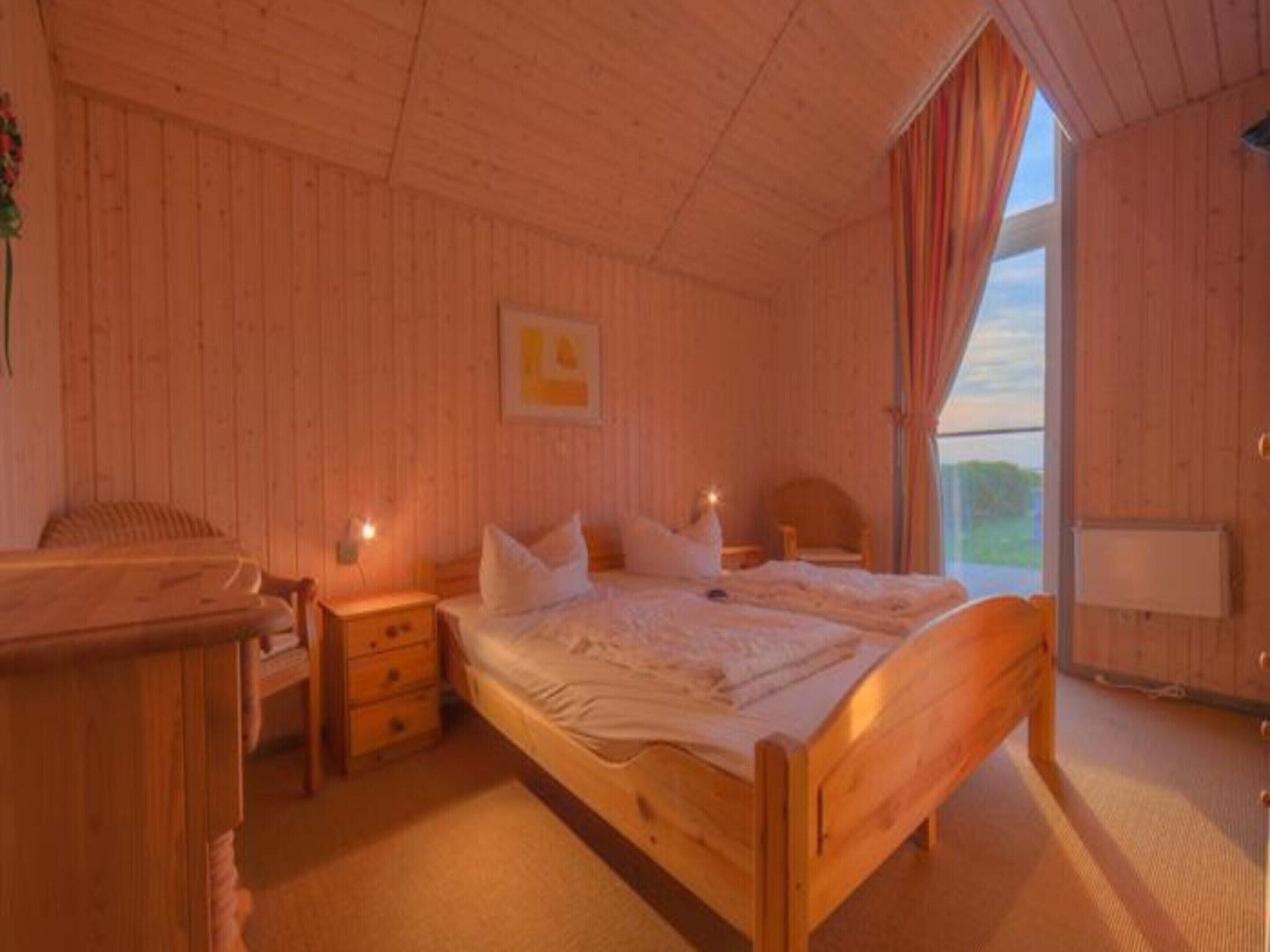 Una stanza in legno con un letto, comodini e una finestra con tende.