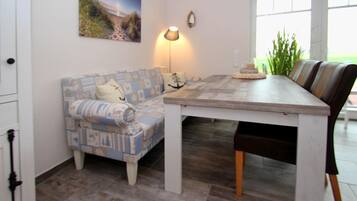 A dining area with a wooden table, a patterned sofa, and a lamp.