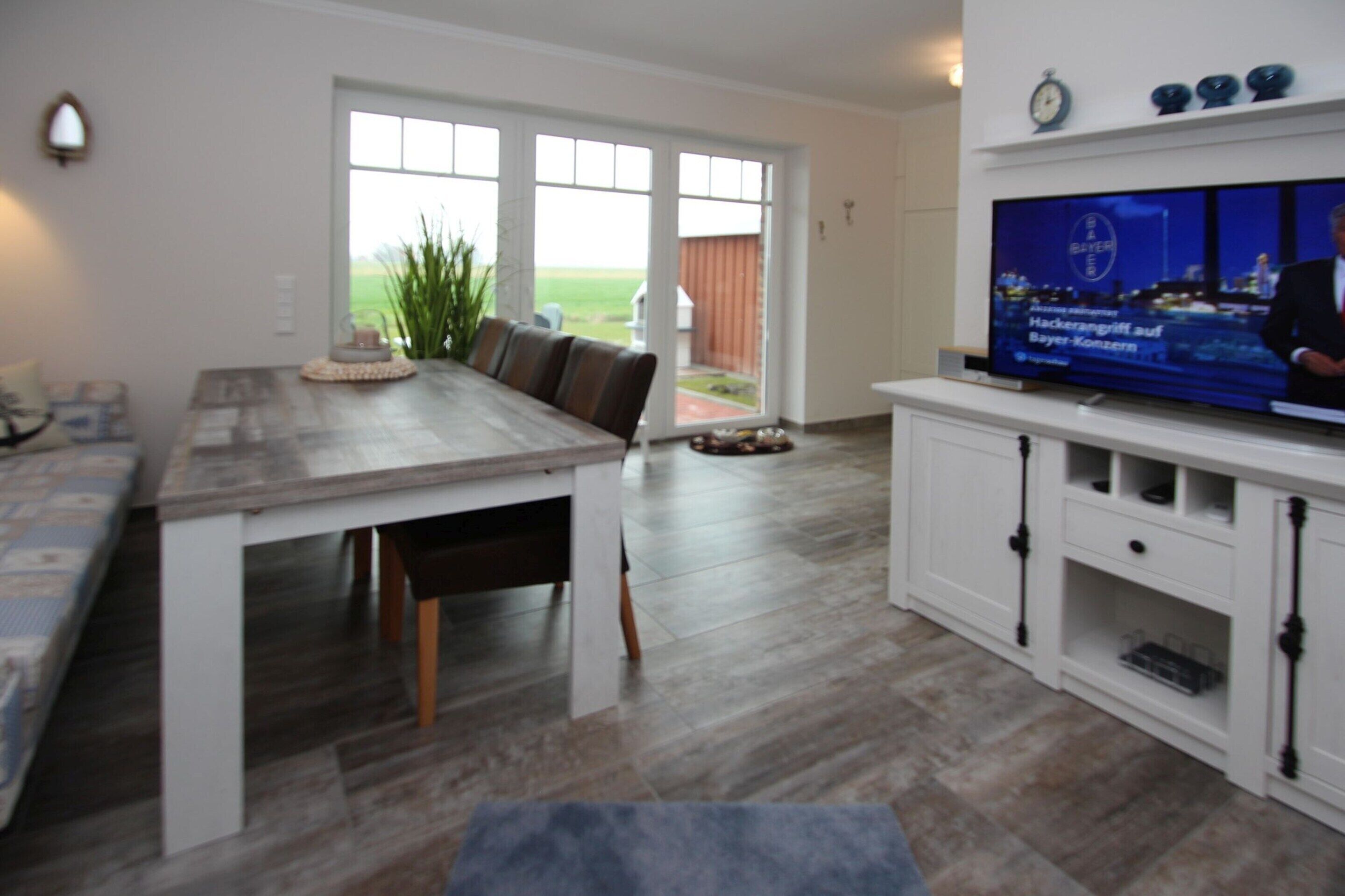 Een moderne keuken met een eethoek, een televisie en uitzicht door de glazen deur.