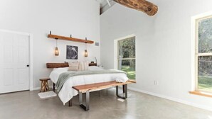 Ein Schlafzimmer mit Bett, Sitzbank und großem Fenster.