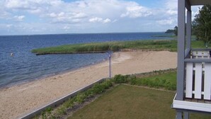 A beach view with a wooden deck and a grassy area. - Exklusives Appartement in Rechlin (Rechlin)