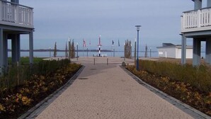 A paved pathway leading to a waterfront area with a lighthouse in the distance. - Exklusives Appartement in Rechlin (Rechlin)