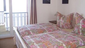 A bedroom with a bed, a nightstand, two pillows, and two wall-mounted pictures. - Exklusives Appartement in Rechlin (Rechlin)
