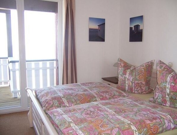 A bedroom with a bed, a nightstand, two pillows, and two wall-mounted pictures. - Exklusives Appartement in Rechlin (Rechlin)