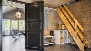 Een modern interieur met een houten trap, een grote zwarte deur en een uitzicht op een eetruimte met een klok.