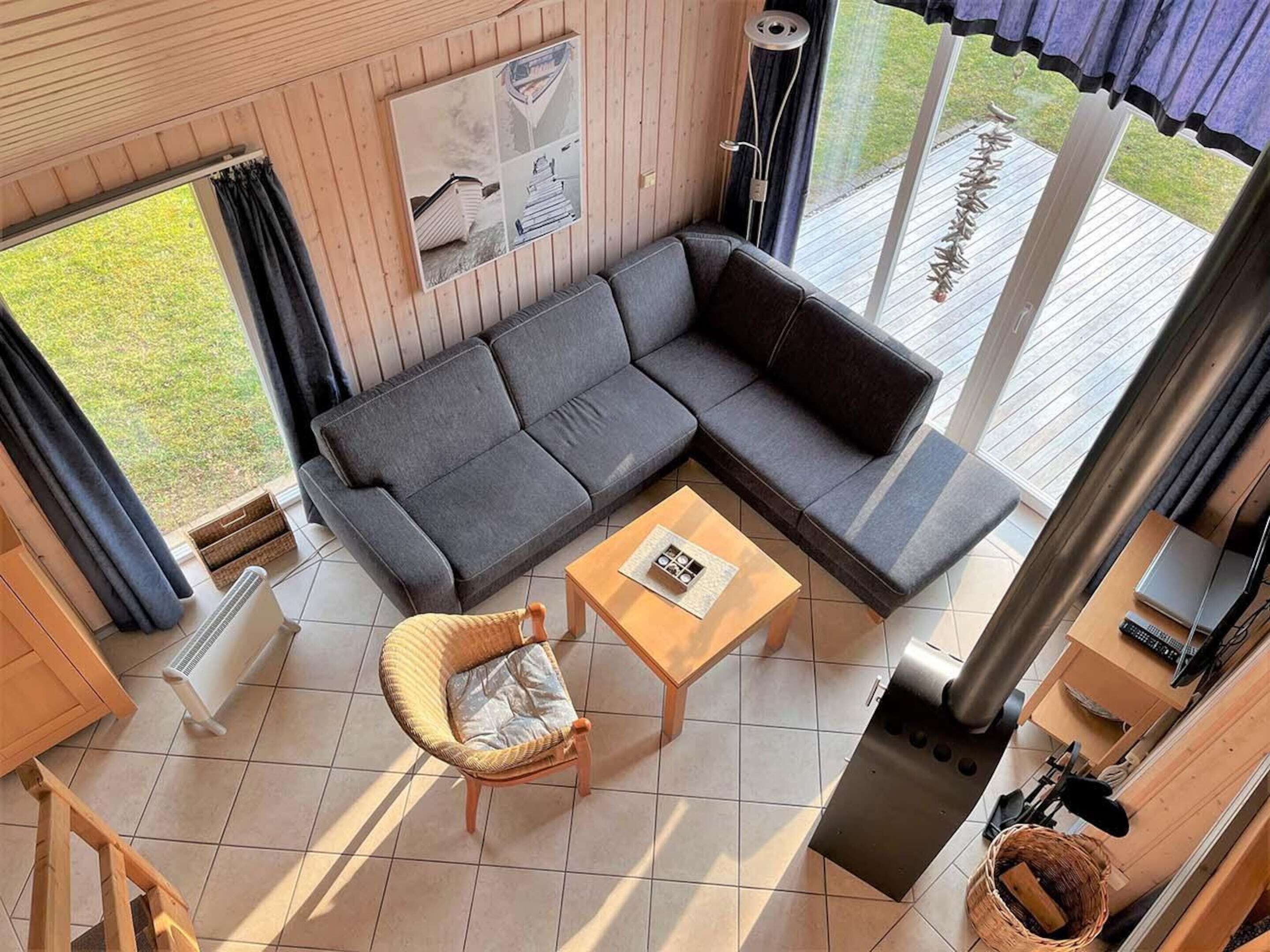 A modern living room with a sectional sofa, a wicker chair, a small wooden table, and a fireplace.