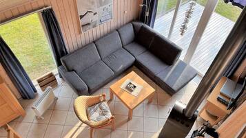 A modern living room with a sectional sofa, a wicker chair, a small wooden table, and a fireplace.