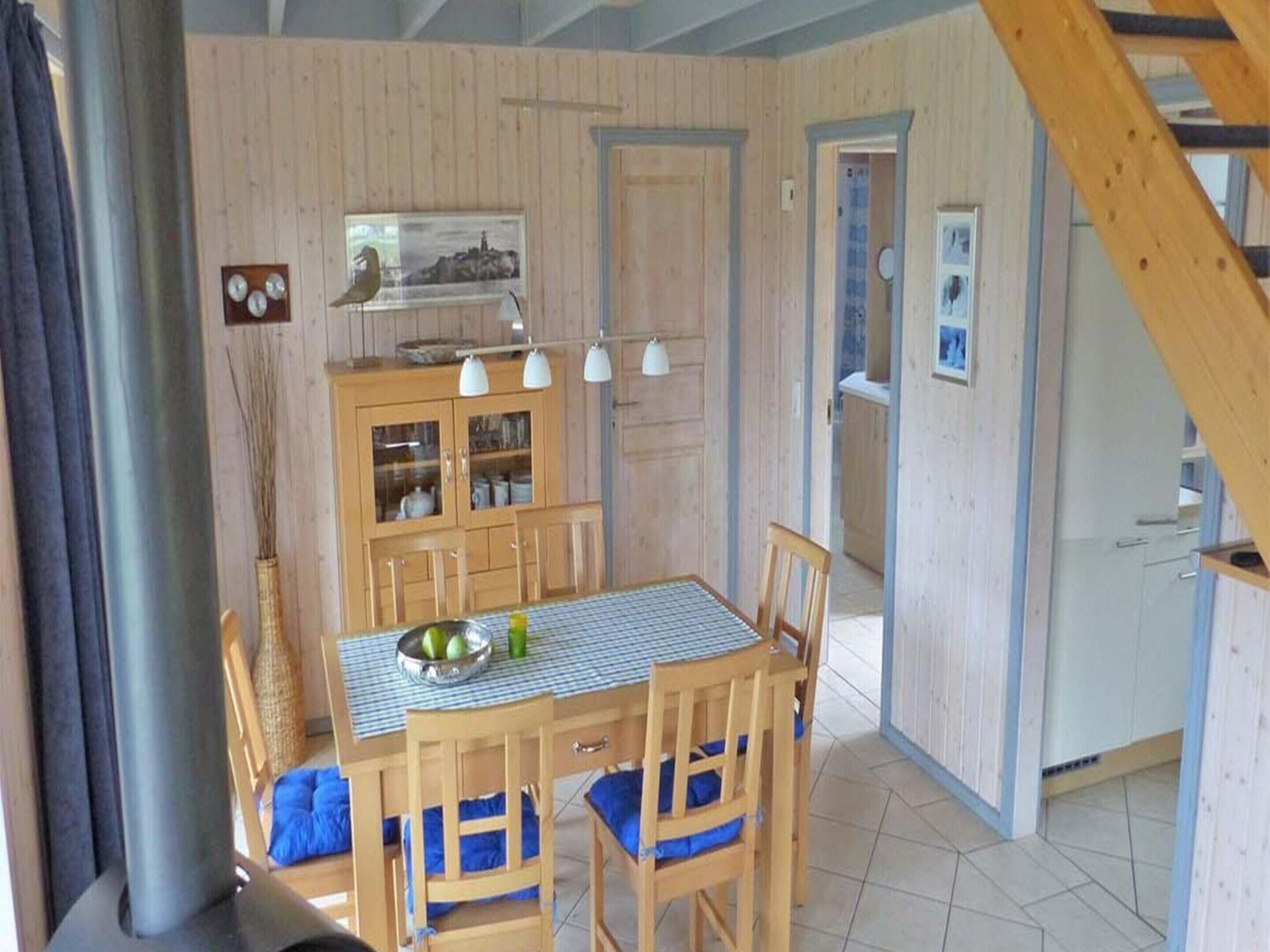 A dining area with a wooden table and chairs, a cabinet with glass doors, and a staircase.