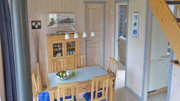 A dining area with a wooden table and chairs, a cabinet with glass doors, and a staircase.