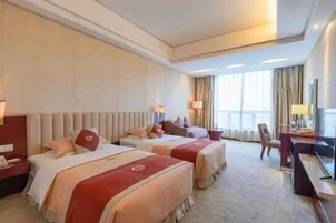 Habitación de hotel con dos camas, un escritorio, una silla y un ventanal con cortinas.