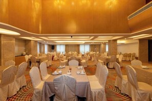 Une salle de banquet avec des tables rondes, des chaises et un sol recouvert de moquette.