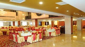 A banquet hall with round tables, chairs, and a red carpet.