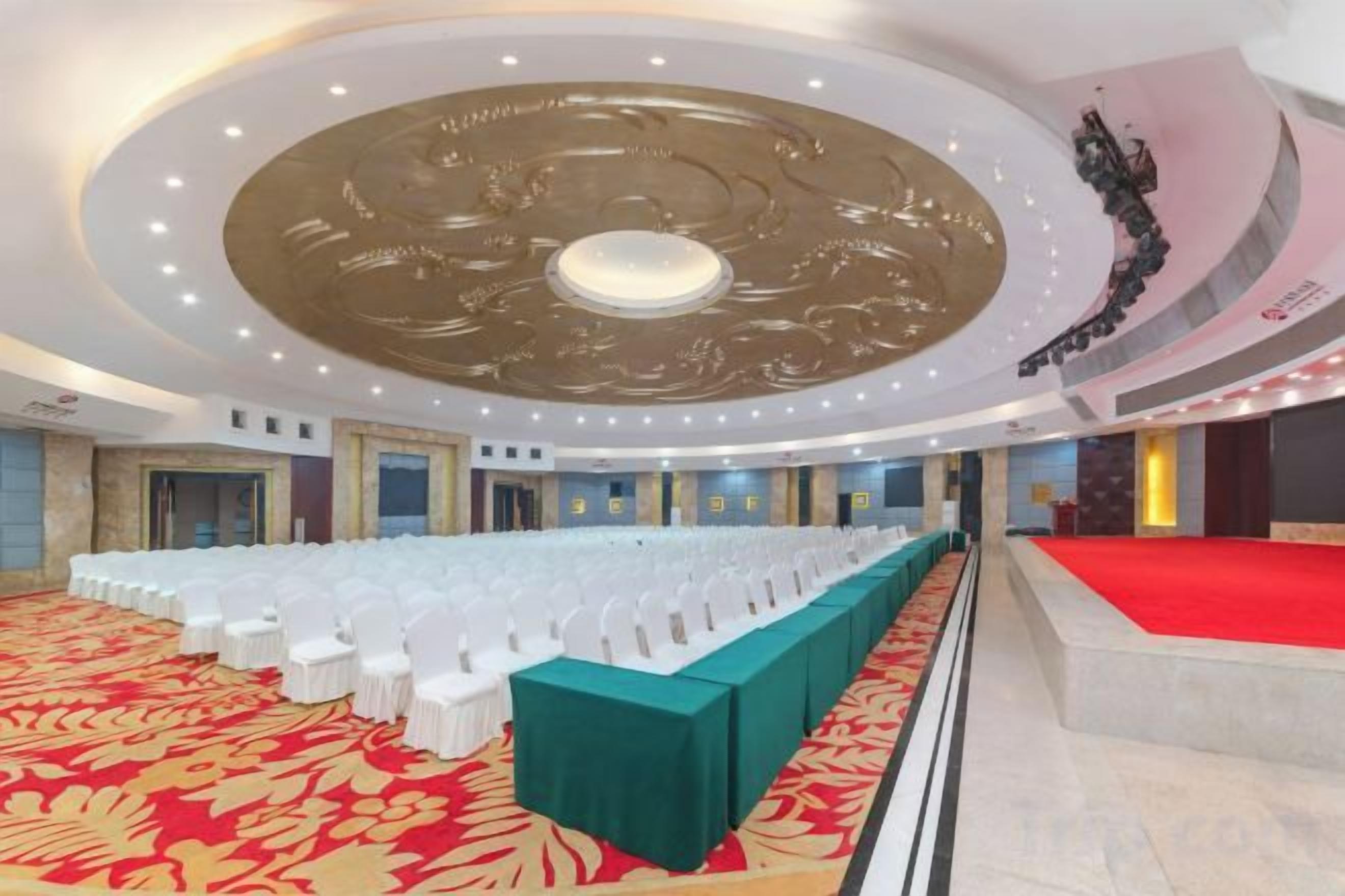 Un salón de banquetes con una larga mesa, alfombra roja y un diseño de techo circular.