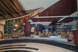 Een moderne lobby met een centraal zitgedeelte met stoelen en een vloer met een patroon.