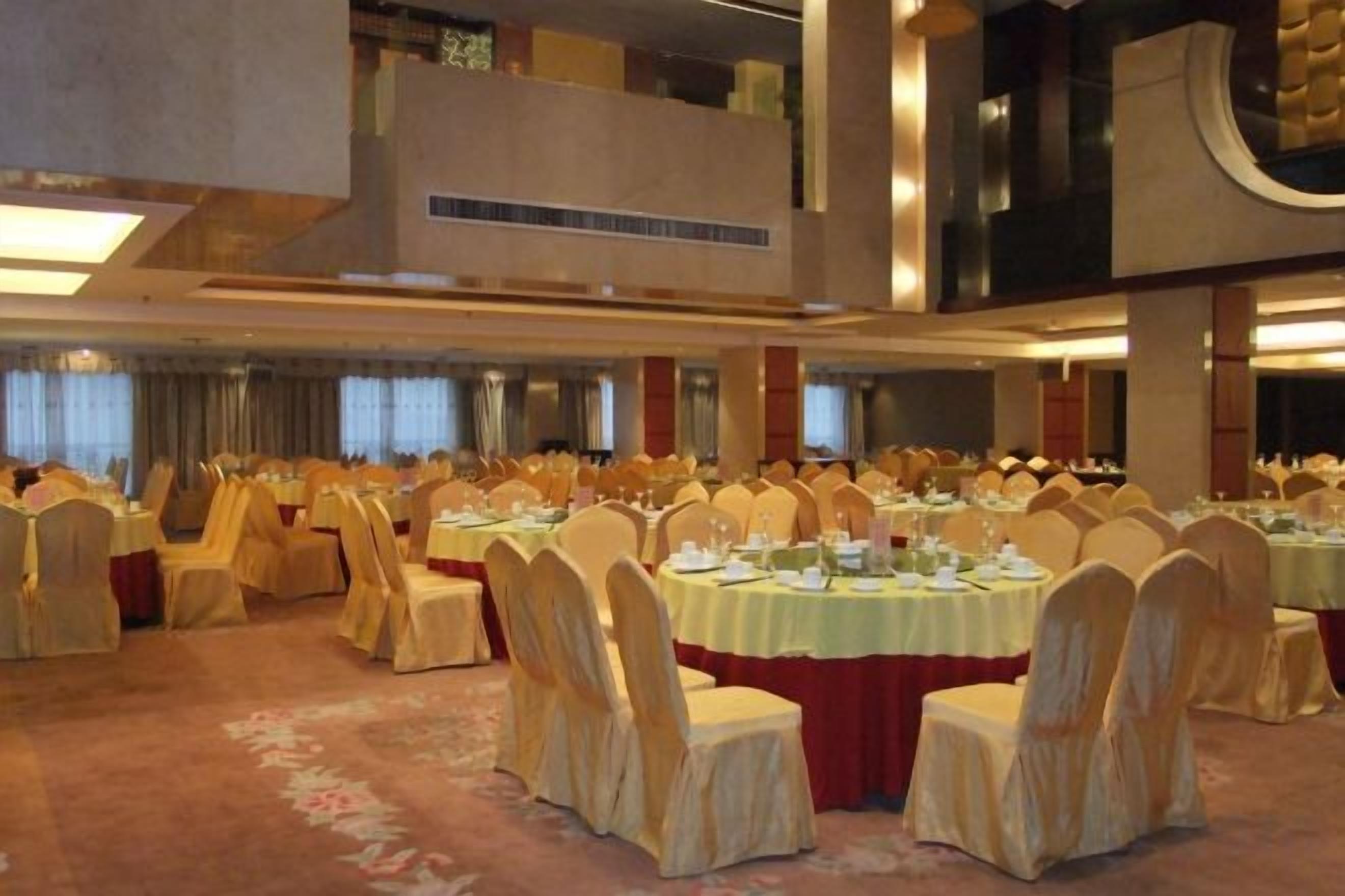 Un salón de banquetes con mesas redondas, sillas y suelo alfombrado.