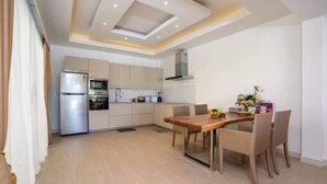 Een moderne keuken met inbouwapparatuur, een eethoek met rieten stoelen en een plafond met inbouwspots.