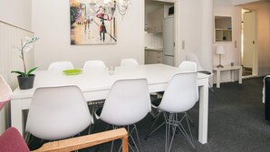 A modern dining area with a white table and chairs, a chandelier, and a painting on the wall. - 6 Person Holiday Home in Give (Give)