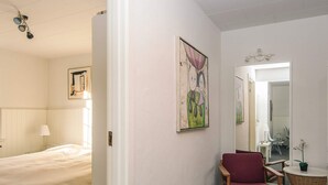 A hotel room with a bed, a chair, a small table, a mirror, and artwork on the walls. - 6 Person Holiday Home in Give (Give)