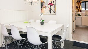A dining area with a white table, black chairs, a chandelier, and a painting of a street scene. - 6 Person Holiday Home in Give (Give)
