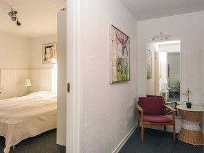 A hotel room with a bed, a chair, a small table, and a mirror.