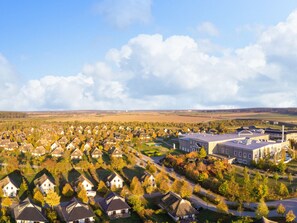 A residential area with houses and a large building, likely a school or community center, surrounded by open fields. - Ferienhaus im Van der Valk Resort in Linstow (Dobbin-Linstow)