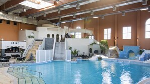 An indoor swimming pool with a bar area, slides, and a staircase leading to a higher level. - Ferienhaus im Van der Valk Resort in Linstow (Dobbin-Linstow)