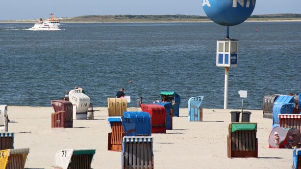 A beach with numbered beach chairs and a lifeguard tower. - Maisonette Wohnung Meerjungfrau, Dornumersiel (Dornum)