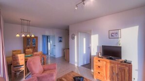A spacious living area with a wooden coffee table, a television on a wooden cabinet, and a dining area with wooden chairs and a table. - Liebevoll Eingerichtetes Appartement (Rechlin)