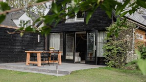 A wooden house with a patio, a table with chairs, and a small garden.