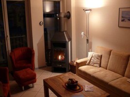 Una sala de estar acogedora con chimenea, un sillón rojo, un sofá beige y una mesa de centro de madera.