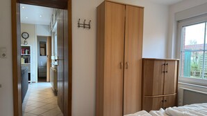 Ein Schlafzimmer mit Bett, Schrank, Heizkörper und Fenster.