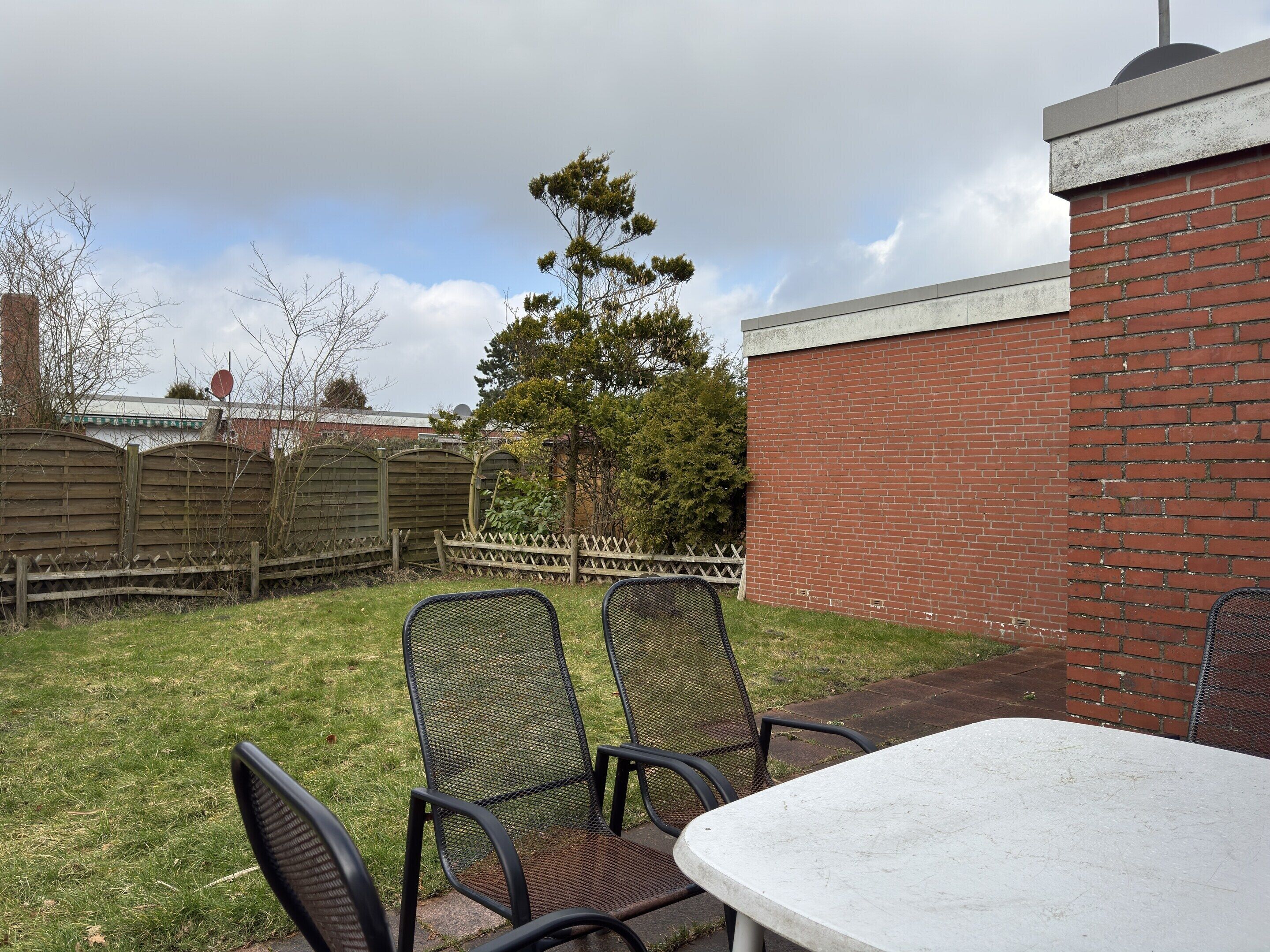 A patio with a table and chairs, a brick wall, and a wooden fence.