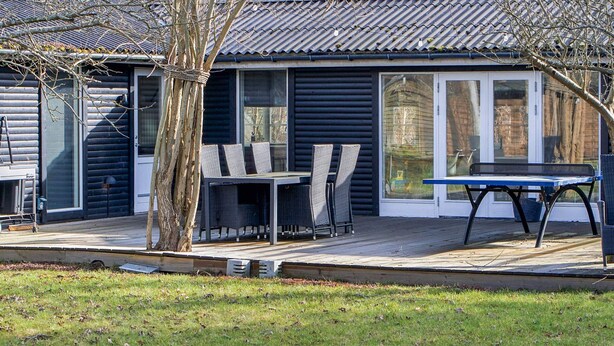 A log cabin with a deck, outdoor seating, and a large window.