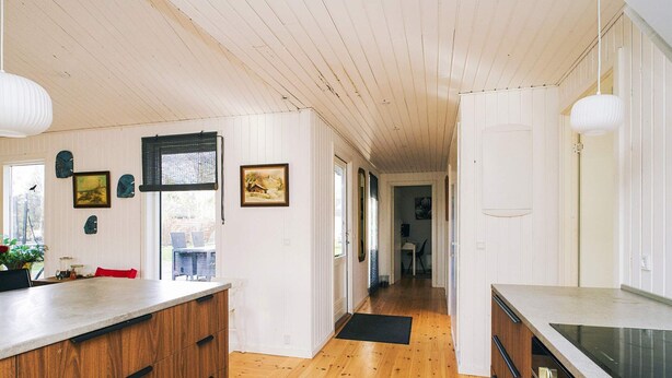 A kitchen with wooden cabinets, a countertop, and a view to the dining area. - 6 Person Holiday Home in Grevinge (Grevinge)